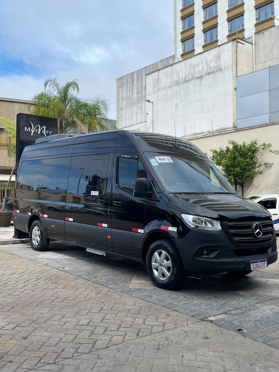 Micro-ônibus executivo preto em frente a hotel